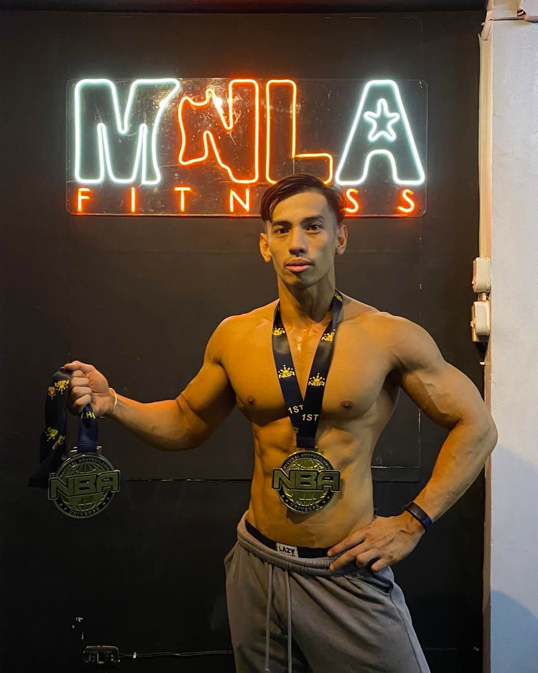 MNLA athlete with competition medal in front of the neon sign